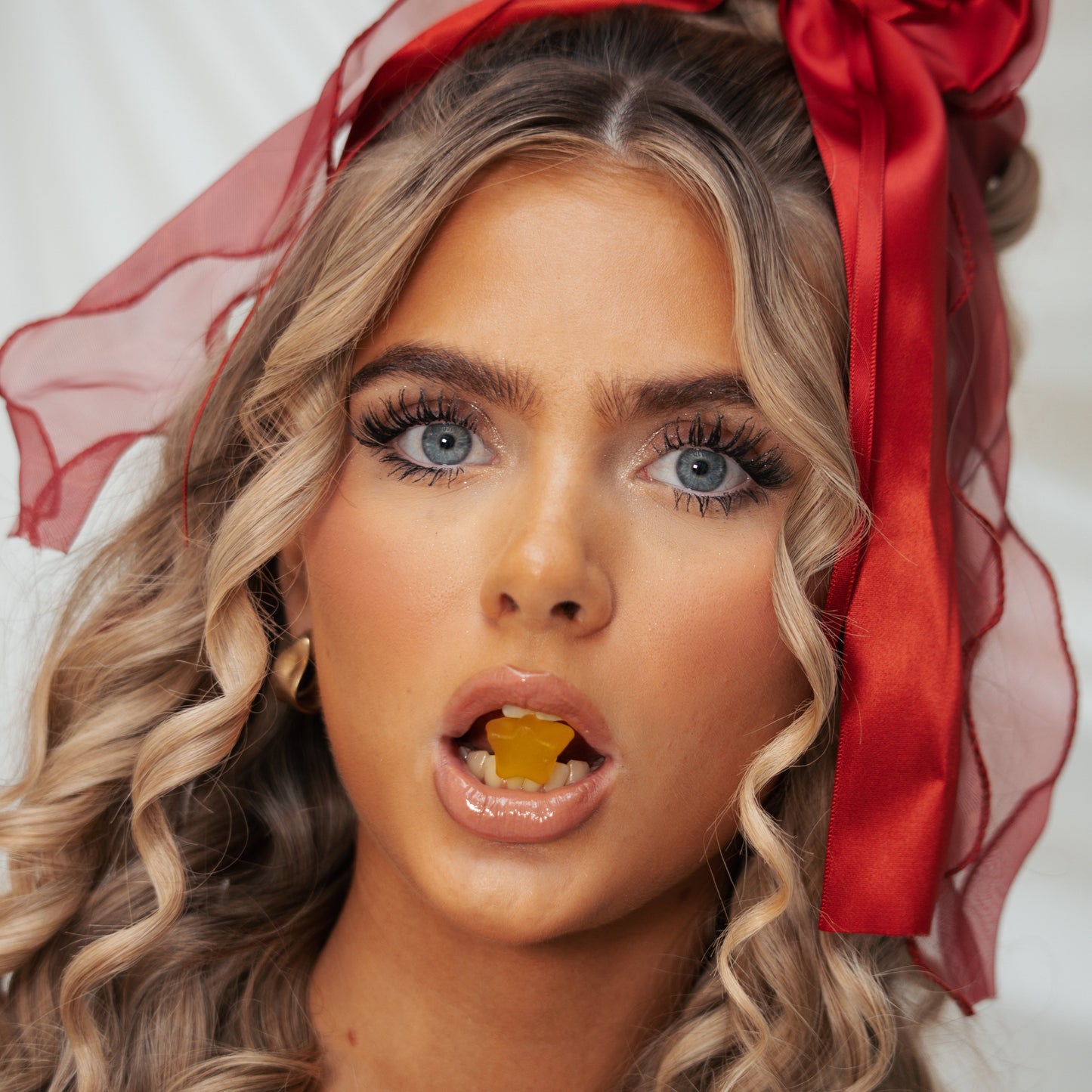 Woman with red ribbon in her hair against a white background