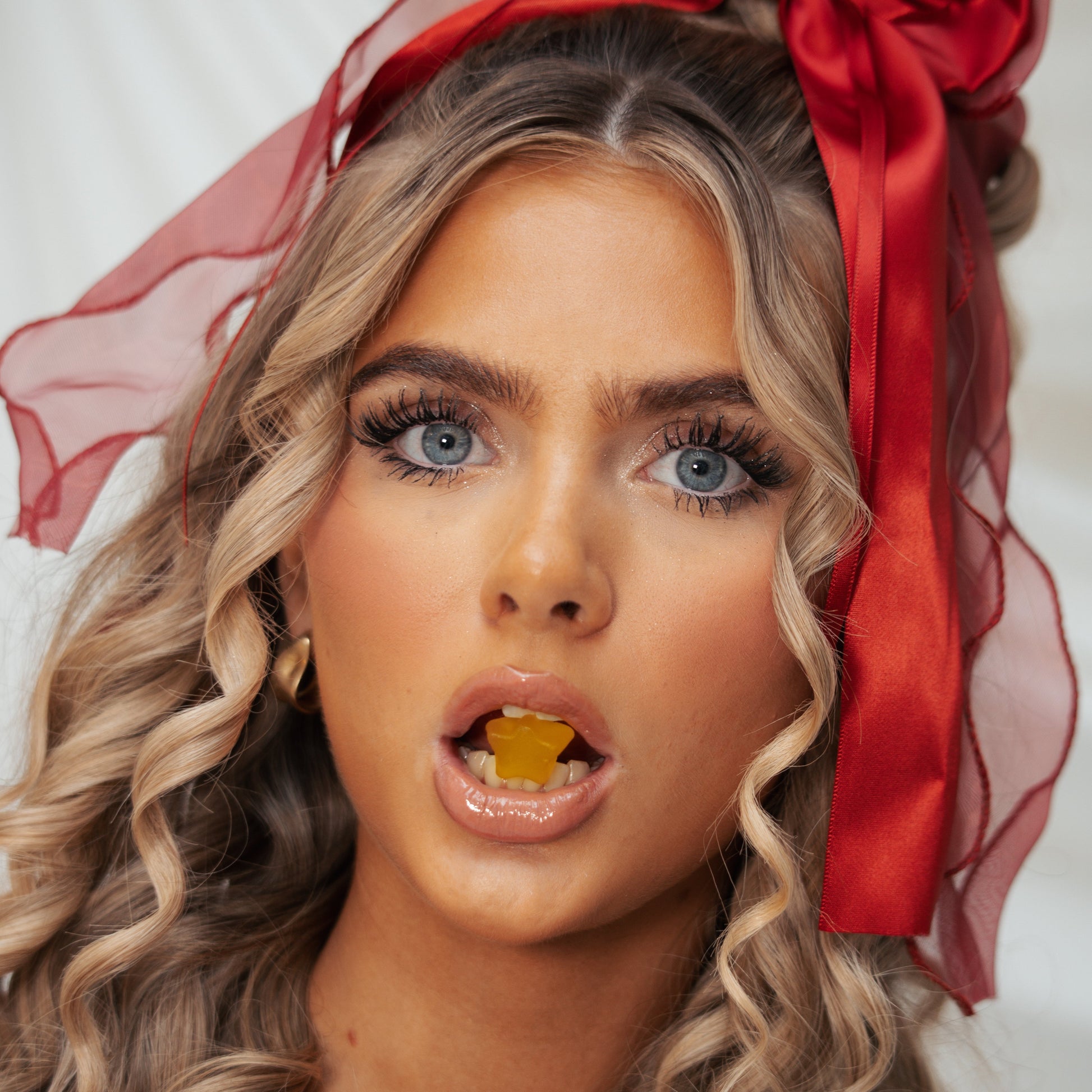 Woman with red ribbon in her hair against a white background