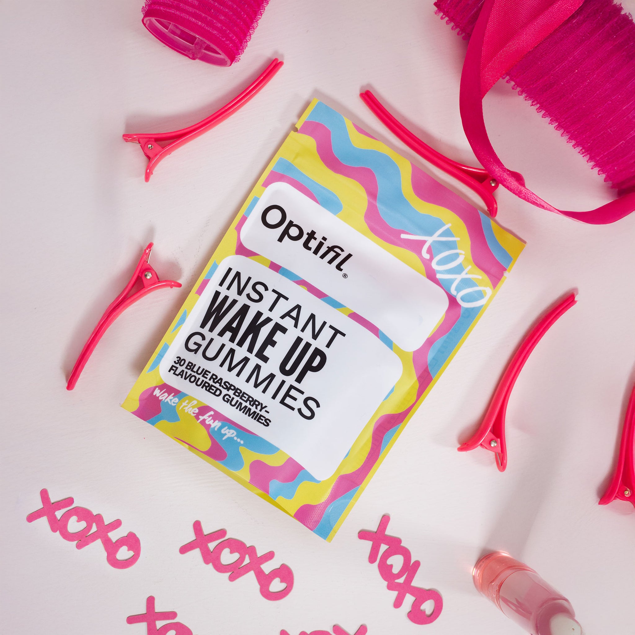 Optifil Instant Wake Up Gummies packaging with pink hair accessories on a light pink background