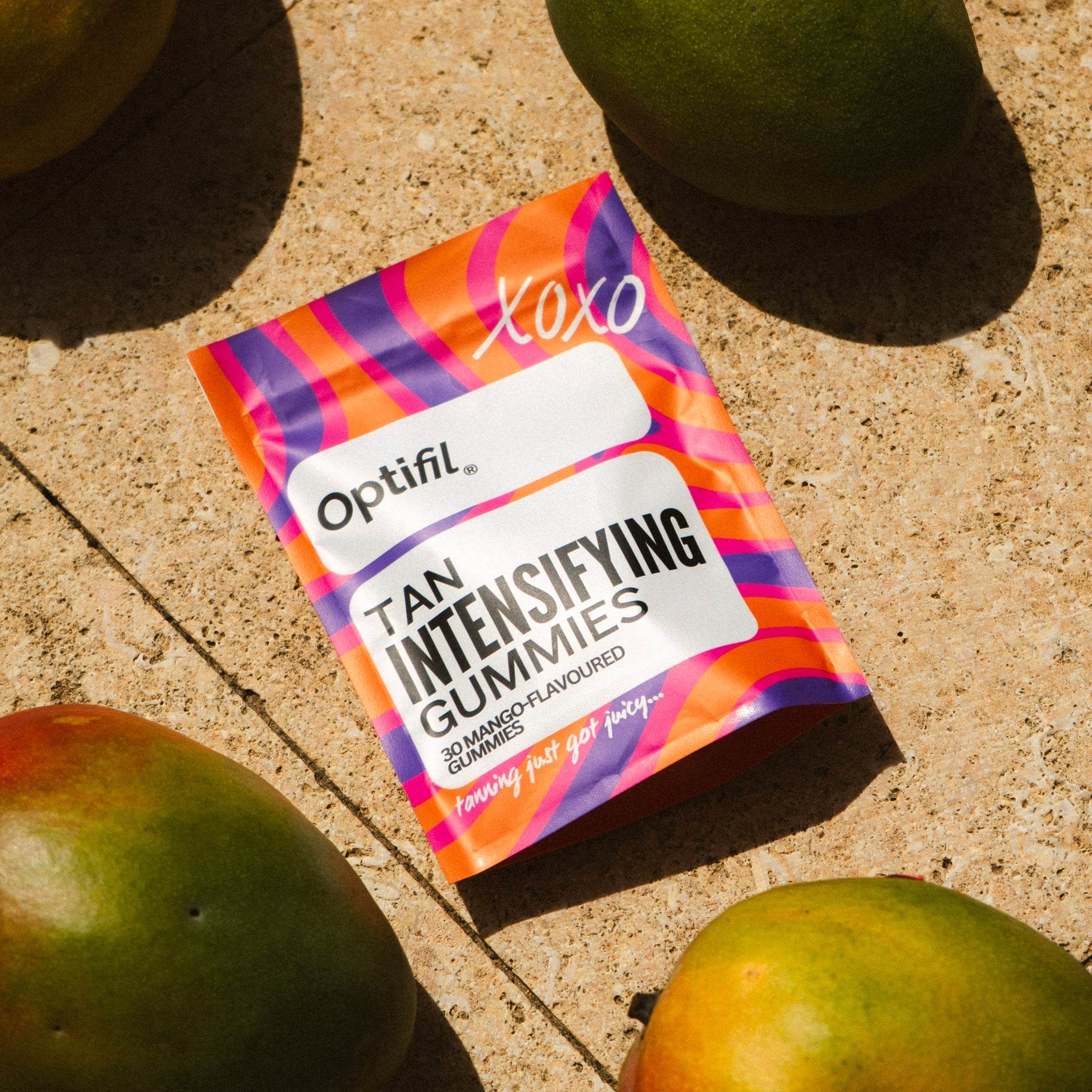 Optifil Tan Intensifying Mango Gummies on a sunlit surface with fresh mangoes - Viral Tan Gummies for skincare and beauty loves in the UK